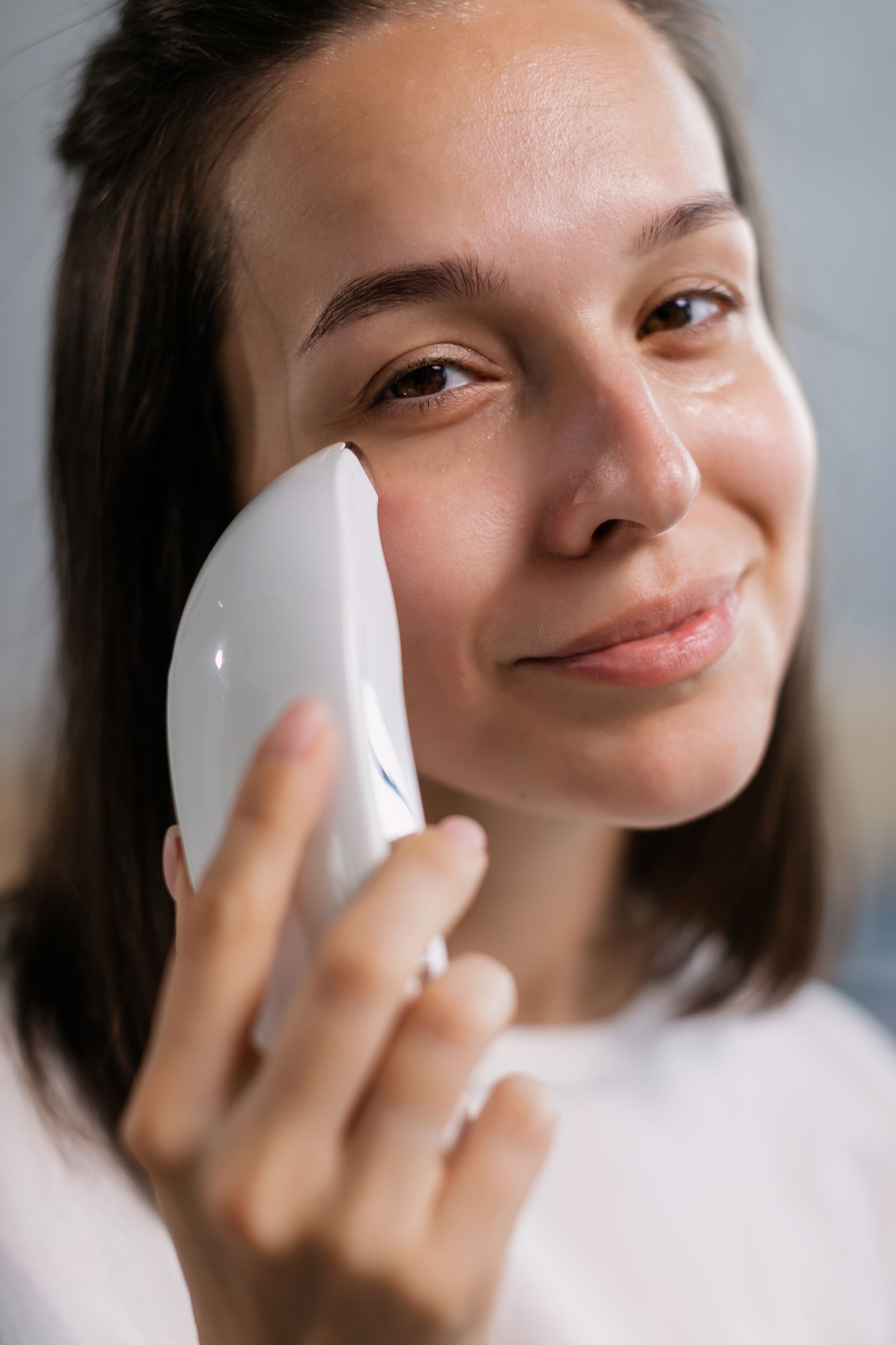 A person using an at-home facial skincare device at a mirror